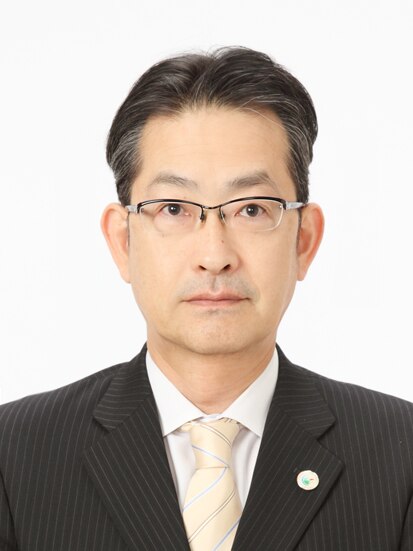 一般社団法人九州観光推進機構　専務理事　渡邉太志の写真（バストショット）。年齢は４０代～５０代。キリッとした顔立ちでメガネをかけスーツを着ている
