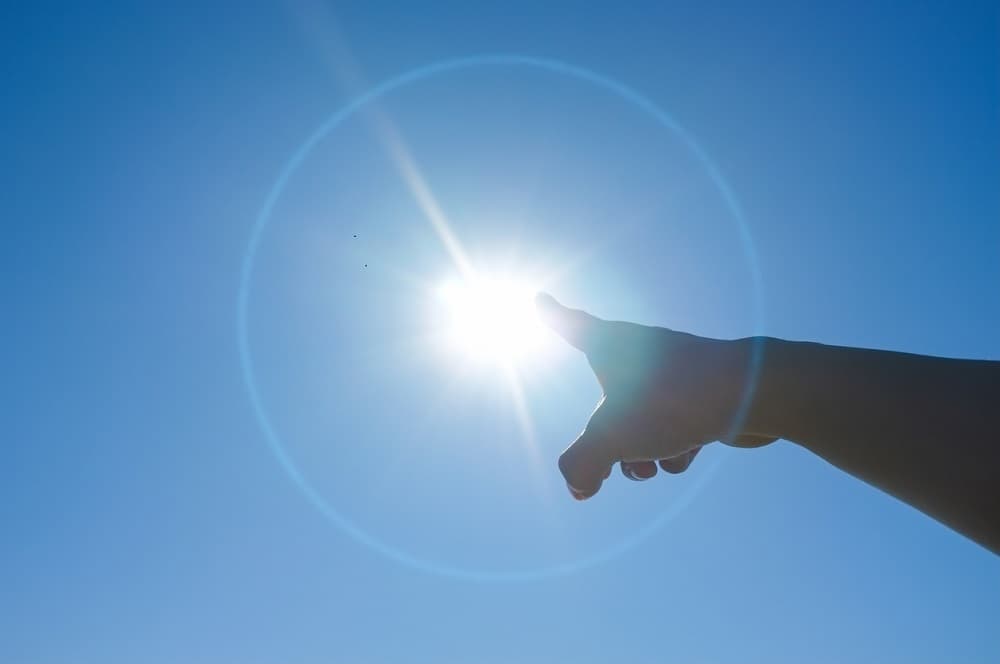 太陽を指さす健康的な手