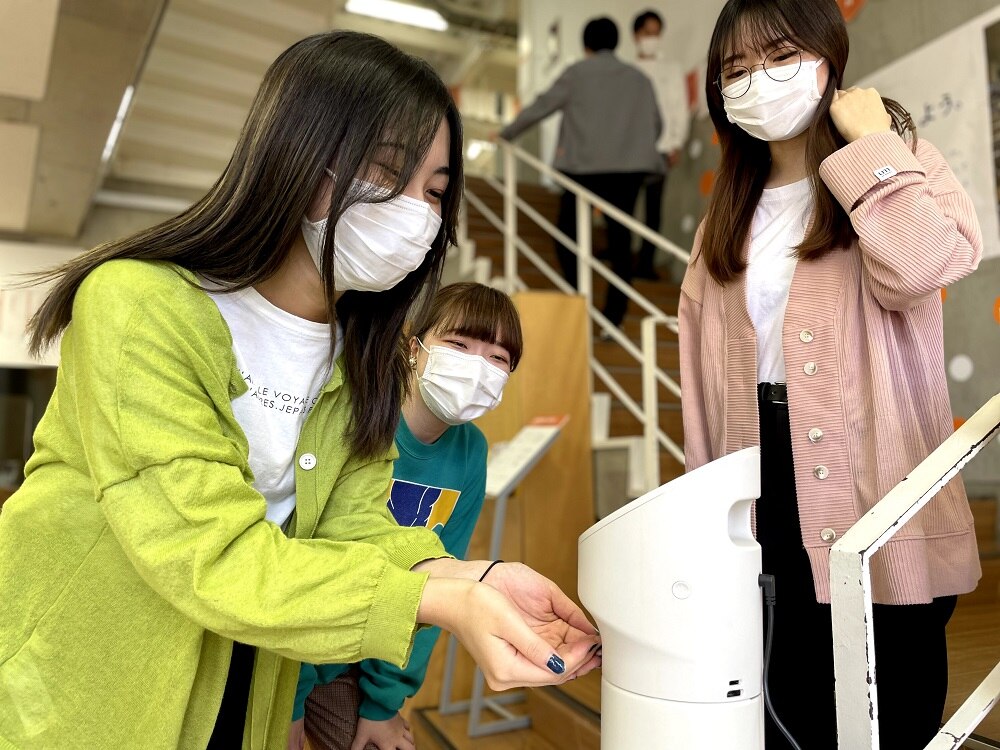 emmyWashに微笑みかけ、除菌液で手を消毒している学生たち