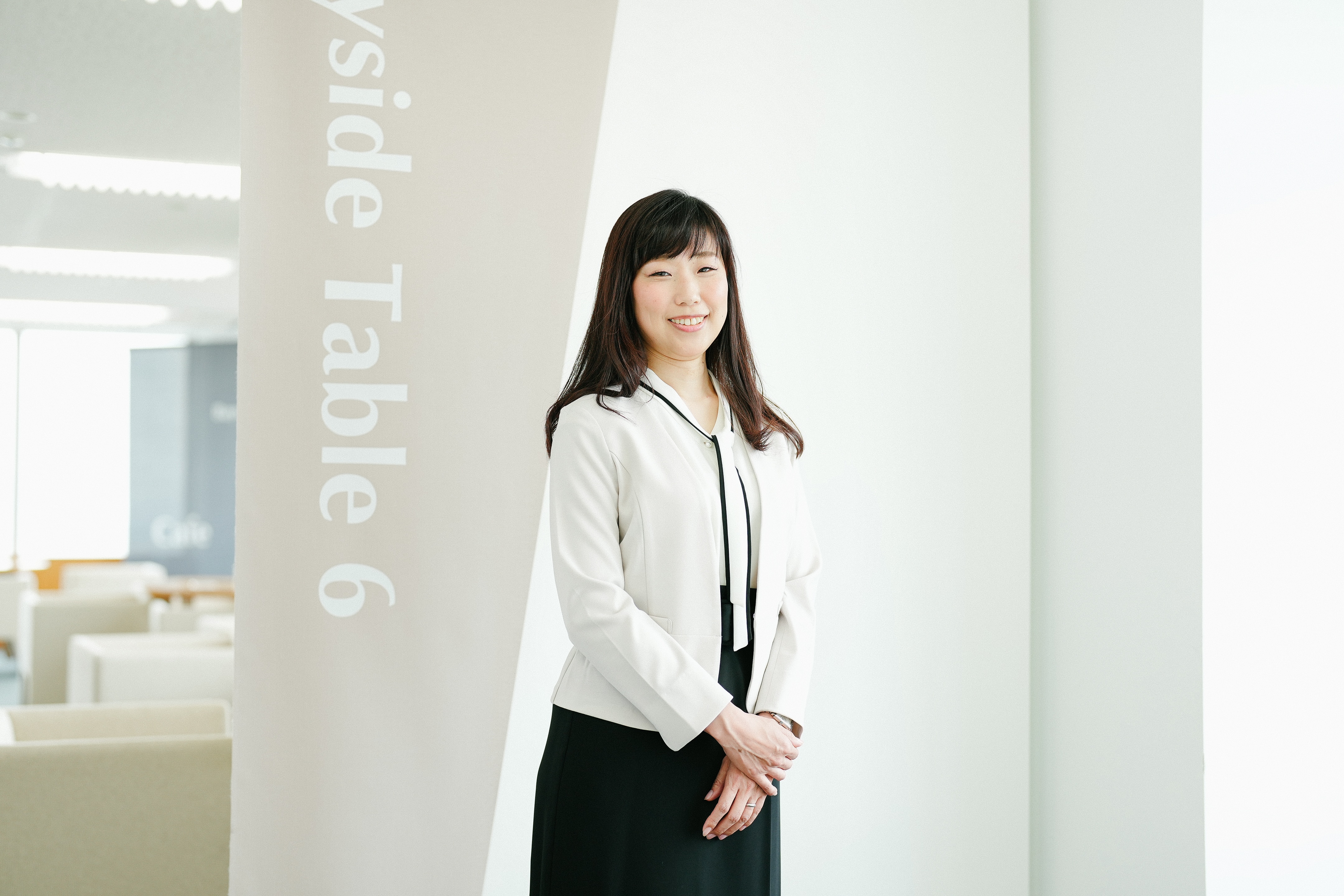 窓の近くで立っている、治験事務局担当者(SMA)のSさん