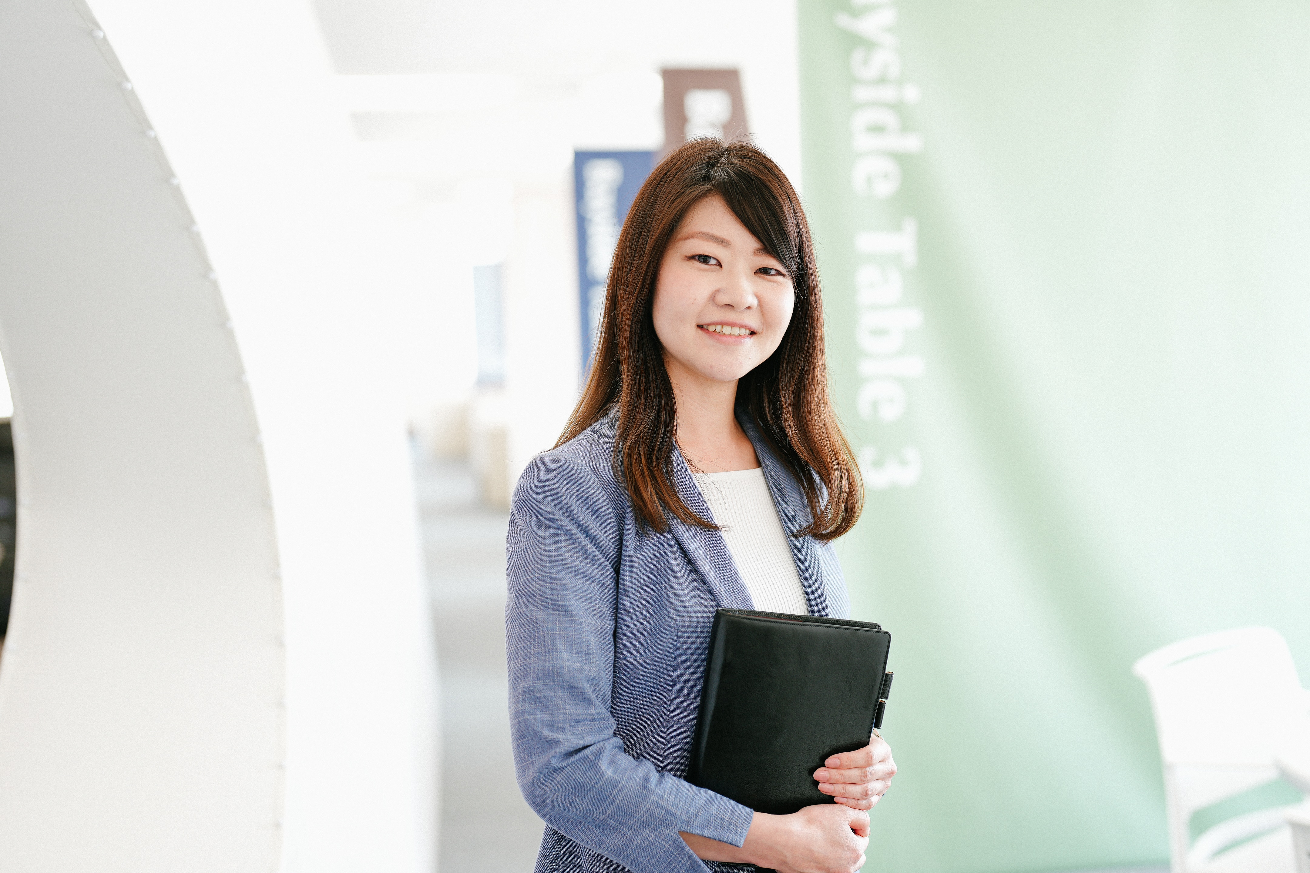 手帳を持って立っている、治験事務局担当者（SMA）のTさん