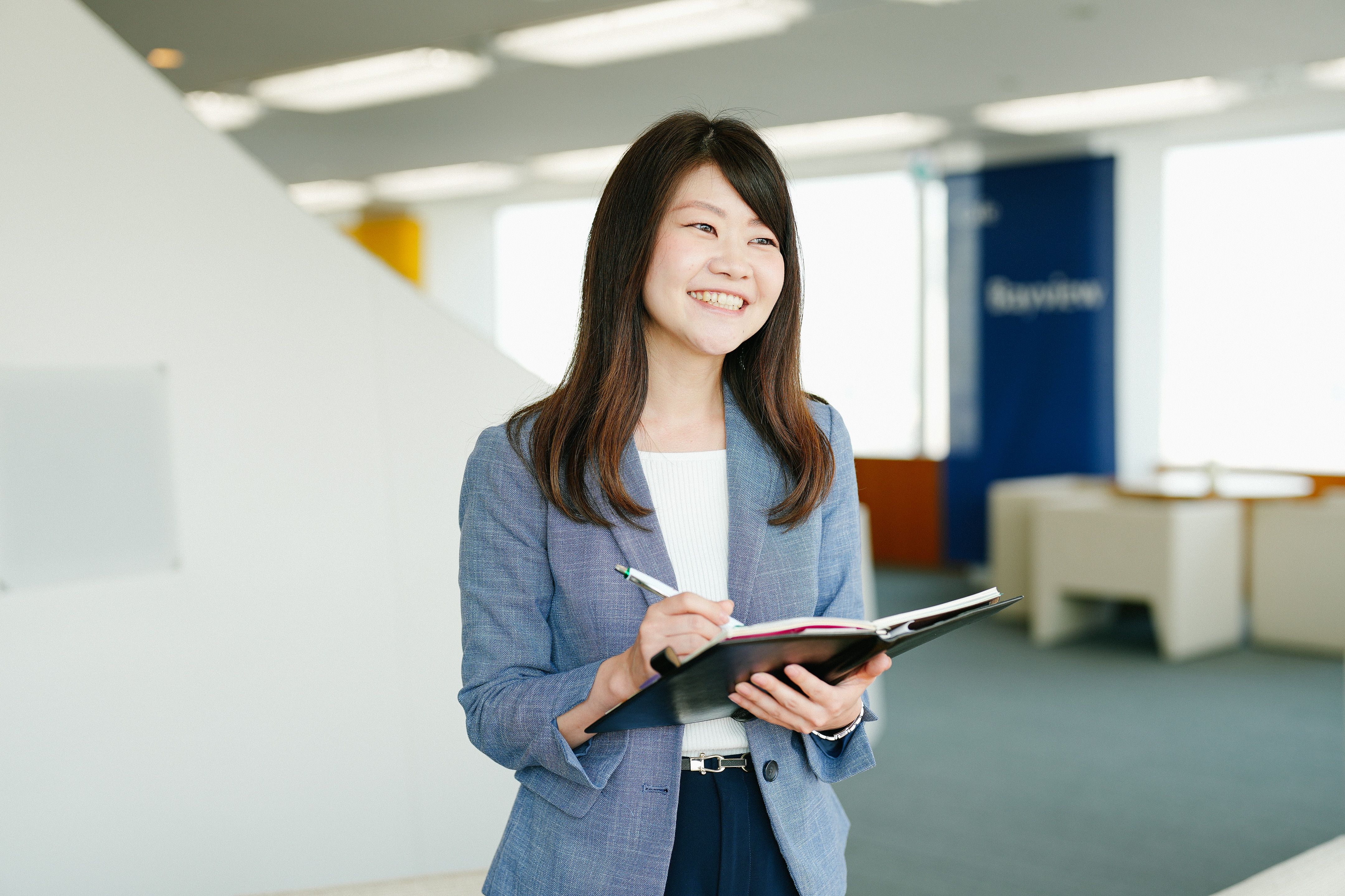 手帳を開いてメモをしている、治験事務局担当者（SMA）のTさん