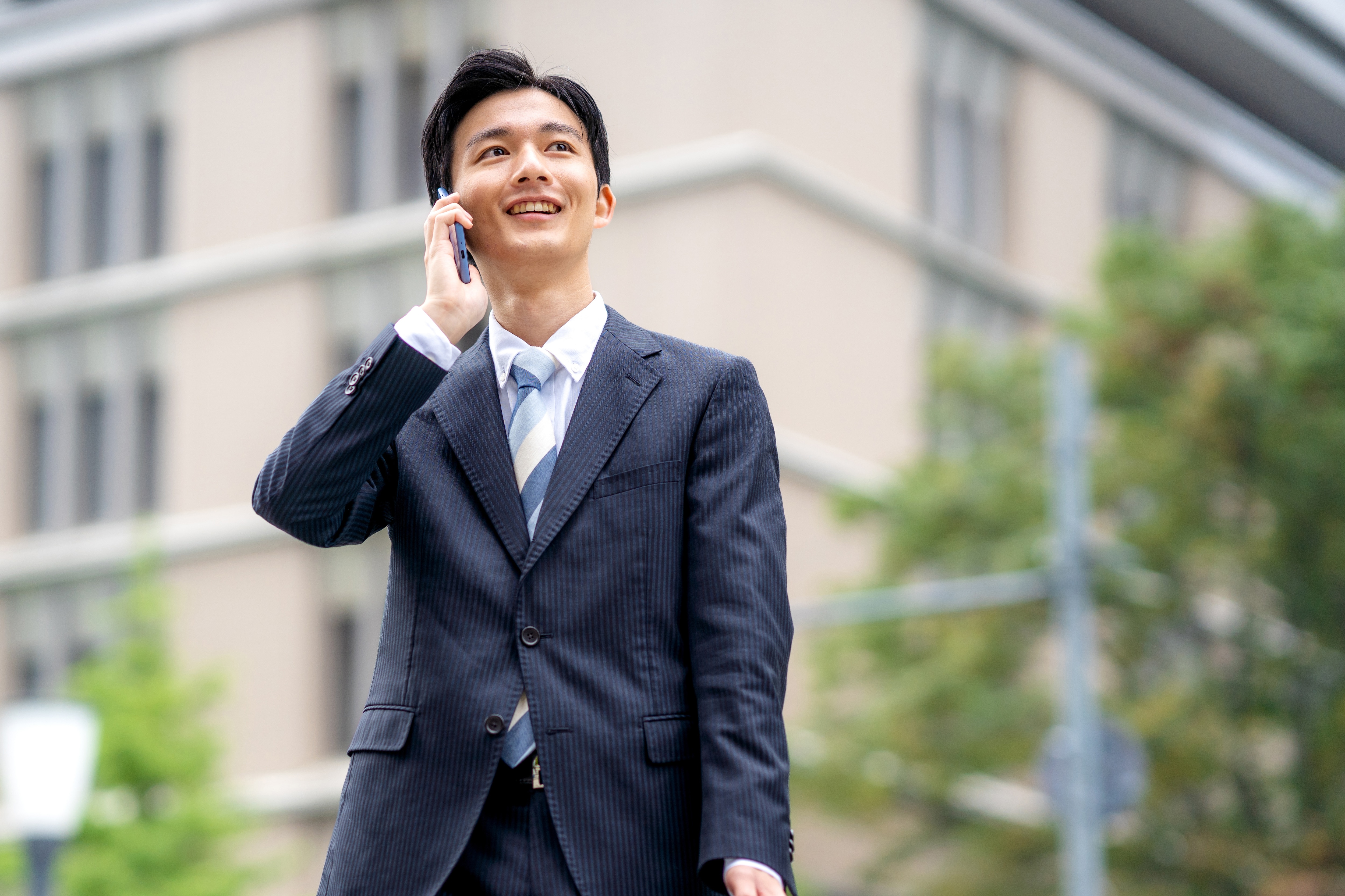 屋外でスマートフォンで電話をしている、営業職の男性