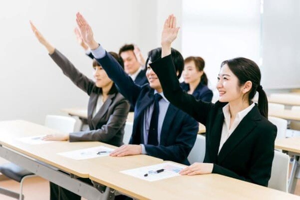 手を挙げる新入社員たち