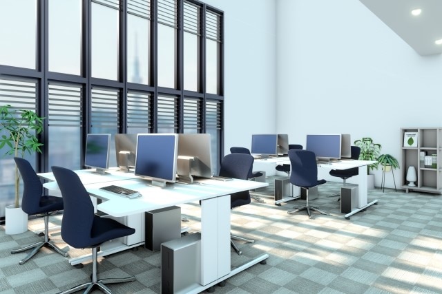 机とPCのある明るいオフィス空間