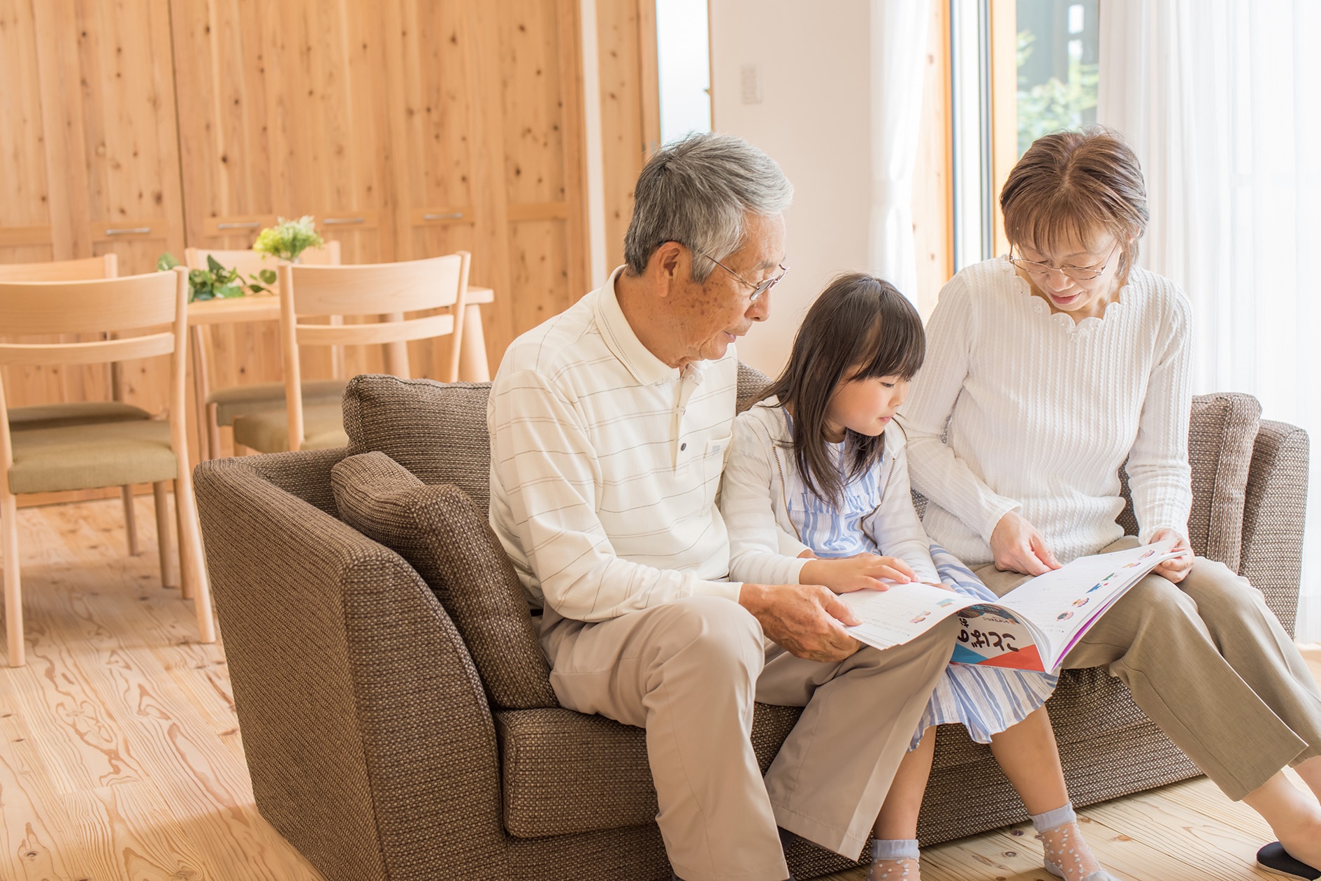祖父母と孫がソファで本を読んでいる写真