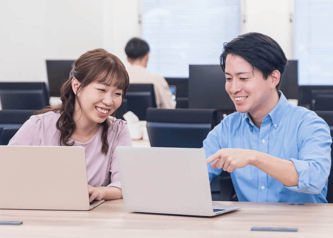 男性と女性がパソコンを見せ合っている様子