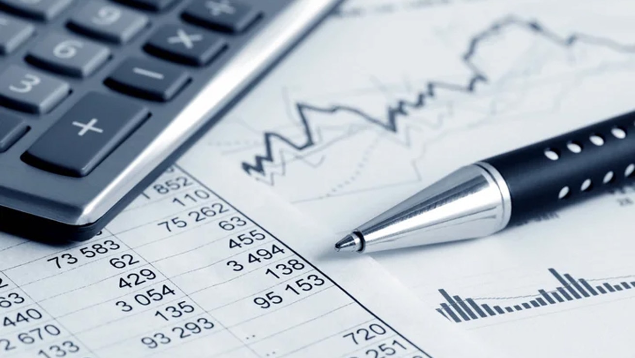 ビジネス文書研修のイメージ。財務資料やグラフを確認しながら報告書やメールを作成するためのデスクに置かれた電卓とペン。