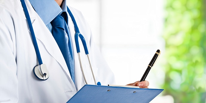 医療・福祉現場での接遇マナー研修イメージ。白衣姿でバインダーとペンを持ち、信頼感を高めるコミュニケーションスキルを表現。