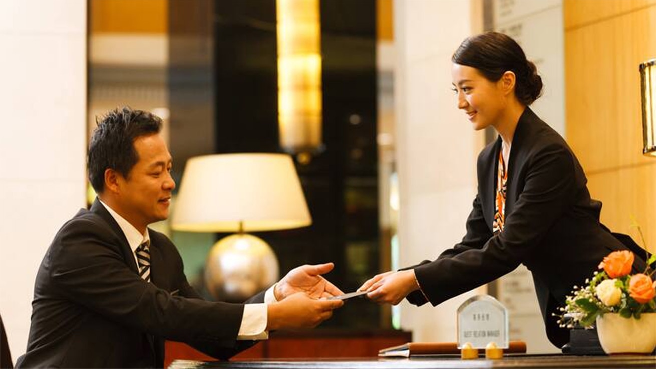 接客力・現場実践トレーニングイメージ。ホテルのフロントで顧客対応を行う様子を表現した写真。