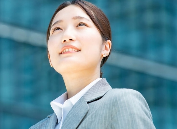 マインドセット研修イメージ。ビジネススーツを着た新入社員がビルを背景に前を見据えて立っている様子。