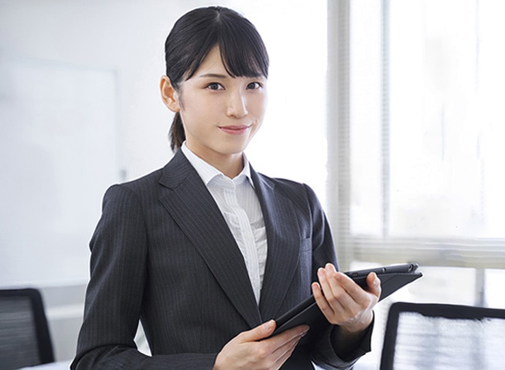 ビジネススーツを着た若手社員が会議室に立っている様子。