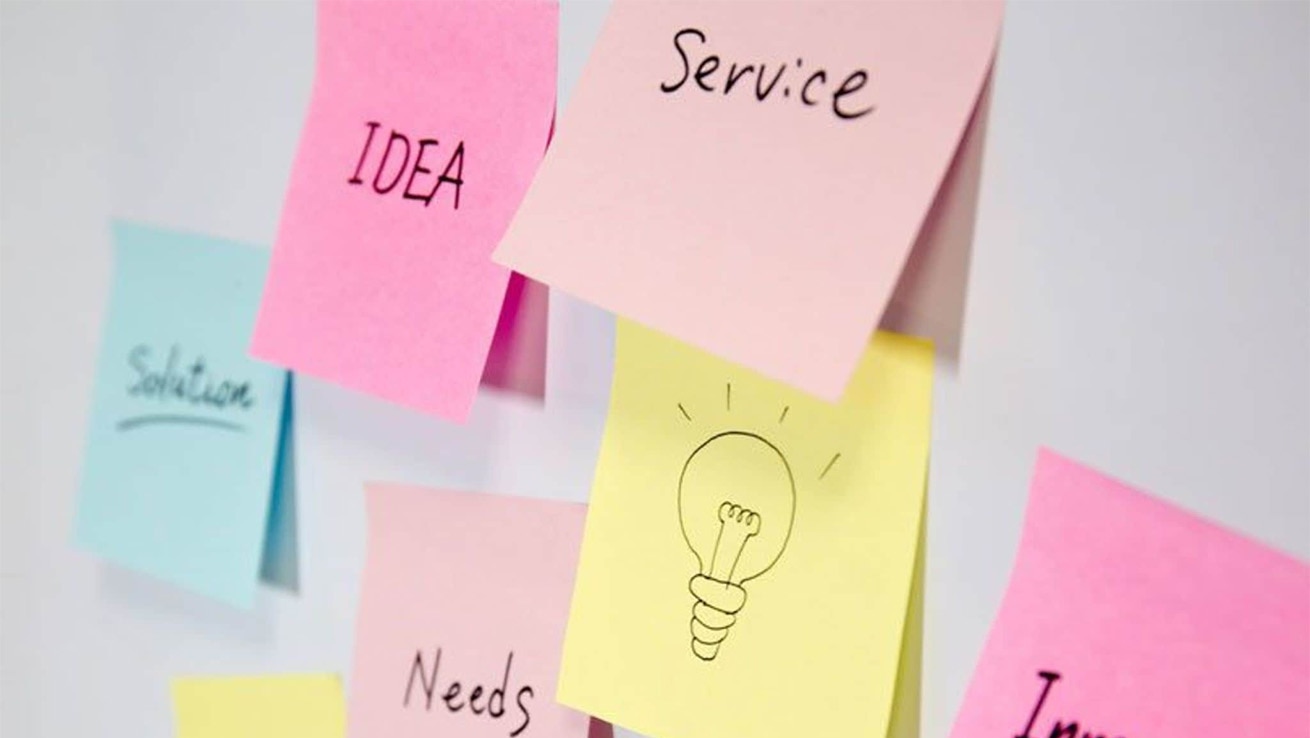 自己成長力・活躍力向上研修イメージ。壁に複数の付箋を貼り、アイデアを出している様子。