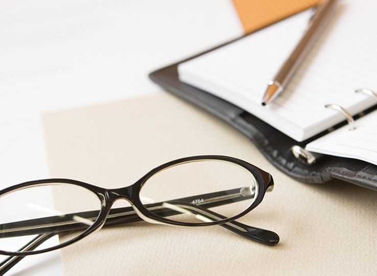 机に眼鏡と手帳が置かれている。