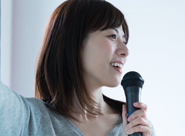 女性活躍推進研修 女性リーダー育成イメージ。マイクを持ち、前方に向かって説明する人物を通じて、リーダーシップや指導力を表現した写真。