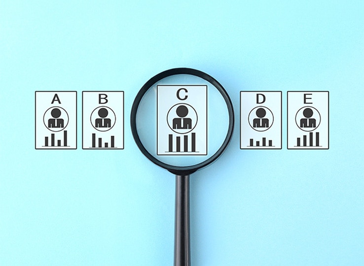 水色の背景に、AからEまでの評価カードが横並びで配置され、中央のCカードを黒い虫眼鏡が拡大している。評価者研修を象徴する、社員評価や選抜をイメージした図。
