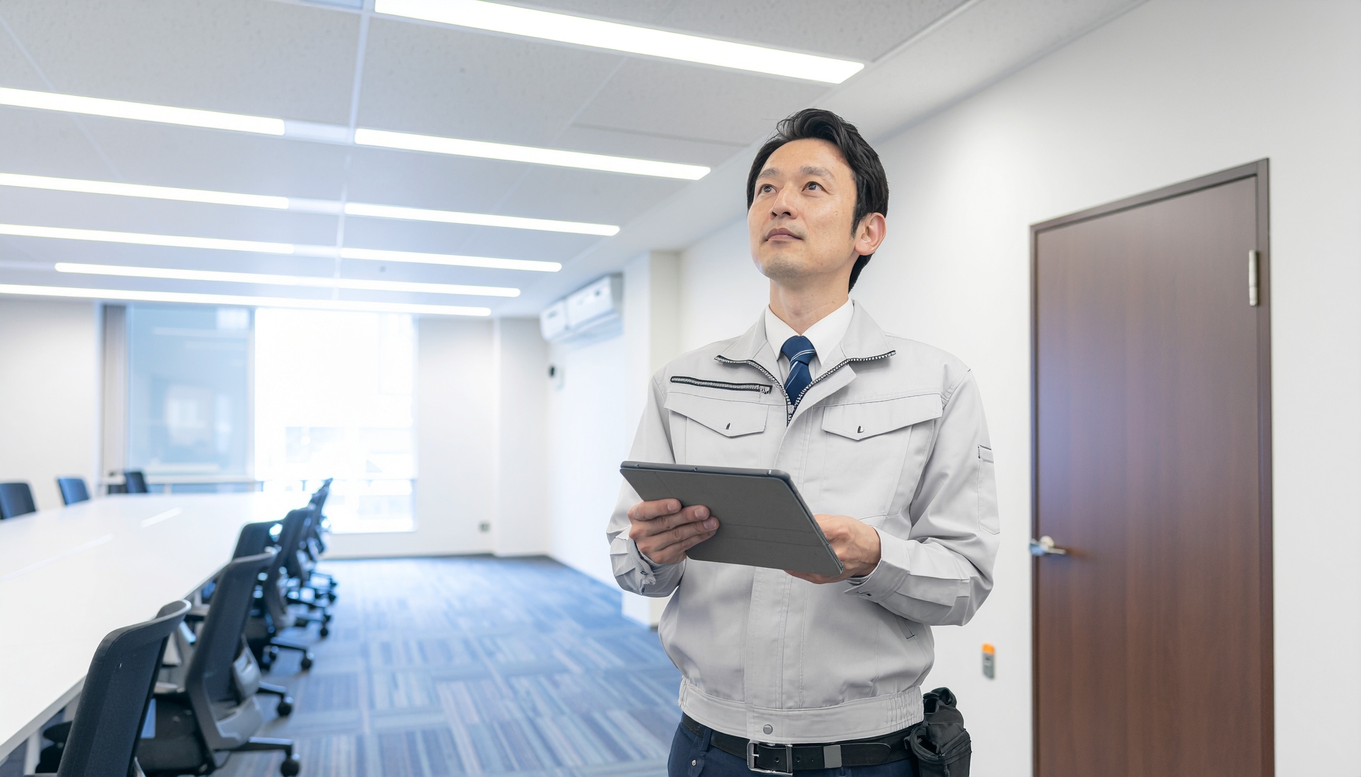 会議室で機器を使用しWi-Fiサーベイを行う作業着姿の男性