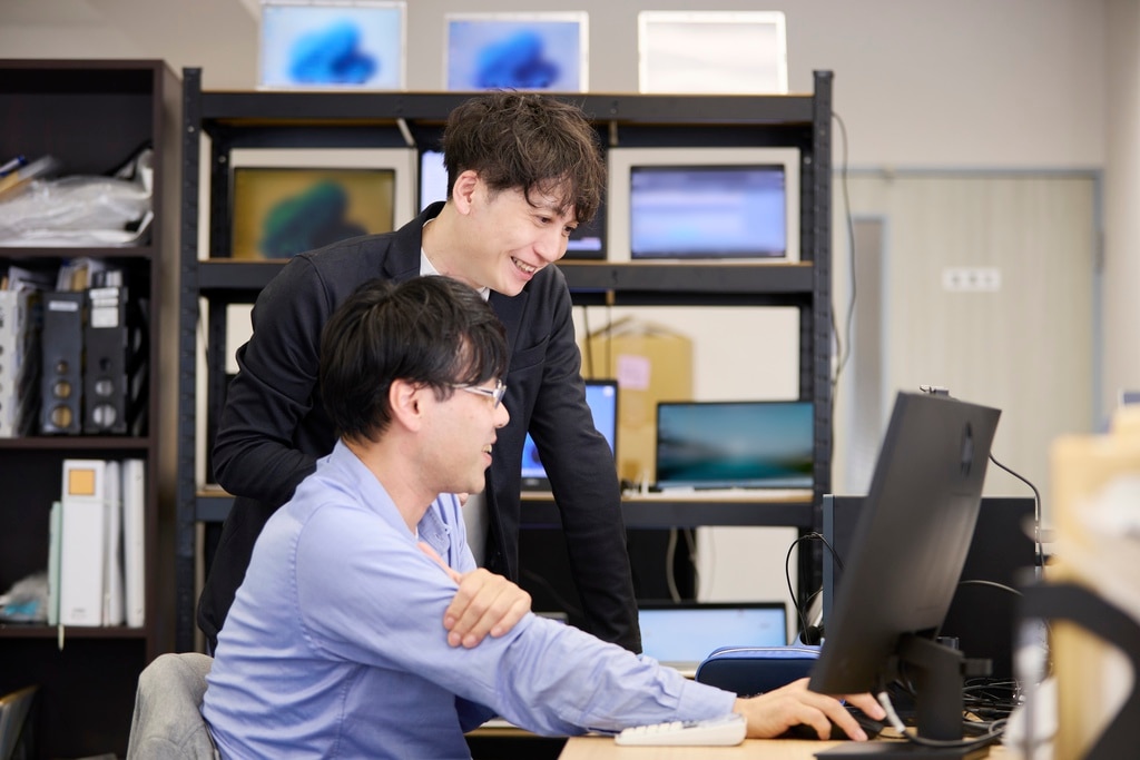 スタッフとPC画面を確認しながら談笑するBIZARQ株式会社 代表 吉岡和樹様