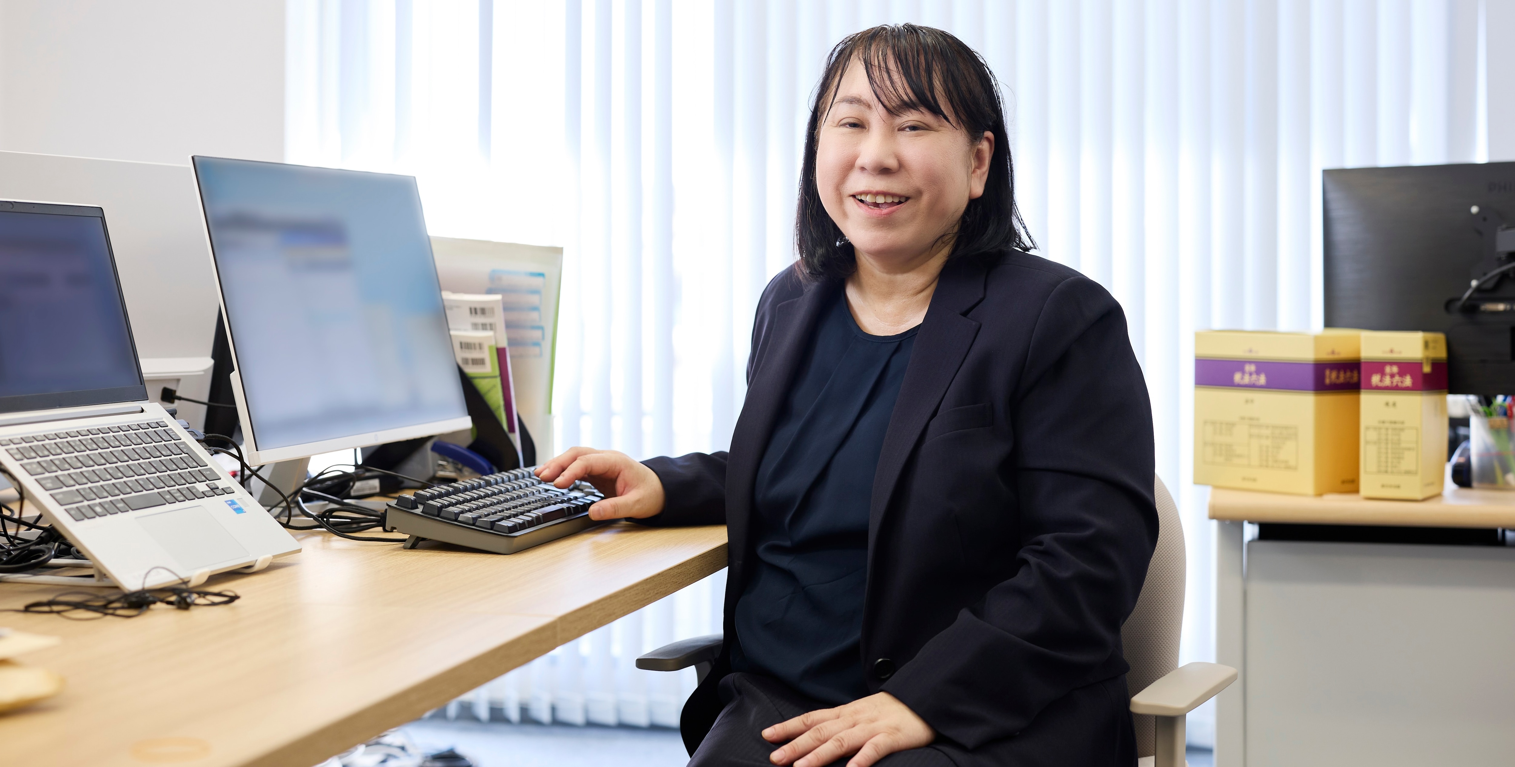 BIZARQ株式会社 柳沼理子様がデスクで笑顔。freee会計導入で業務効率化を実現。