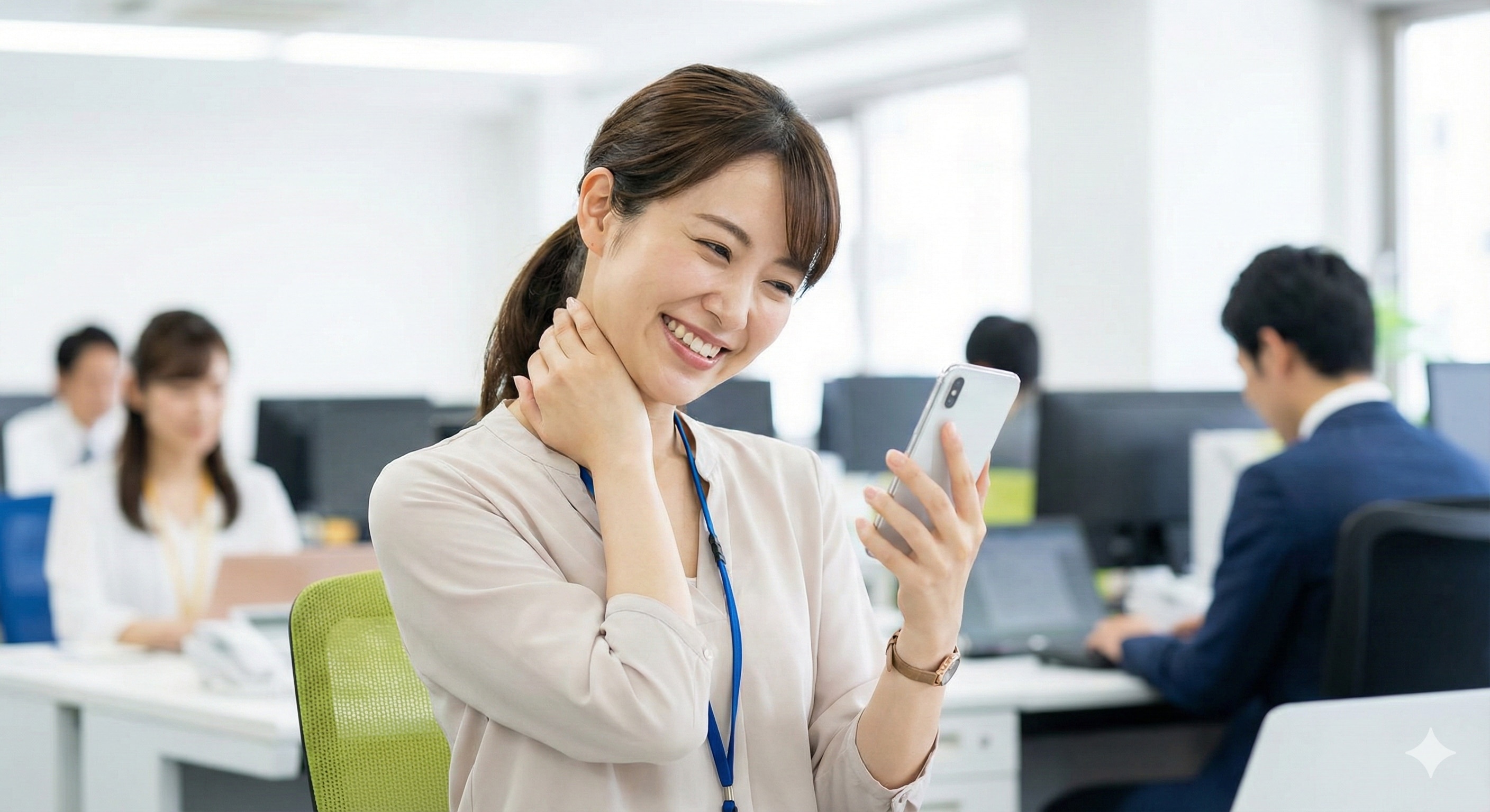 スマートフォンを見ながら、オフィスで軽いストレッチをして笑顔になっている従業員