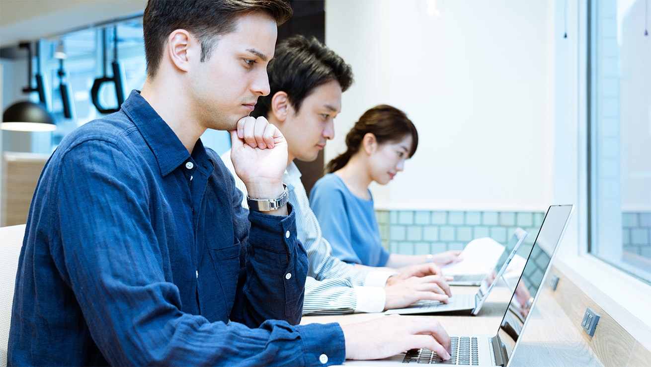 外国籍社員がノートパソコンに向かっている