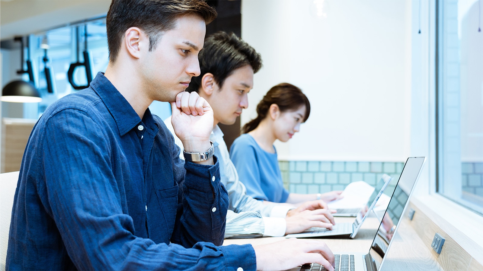 外国籍社員が日本人社員とパソコンに向かっている姿