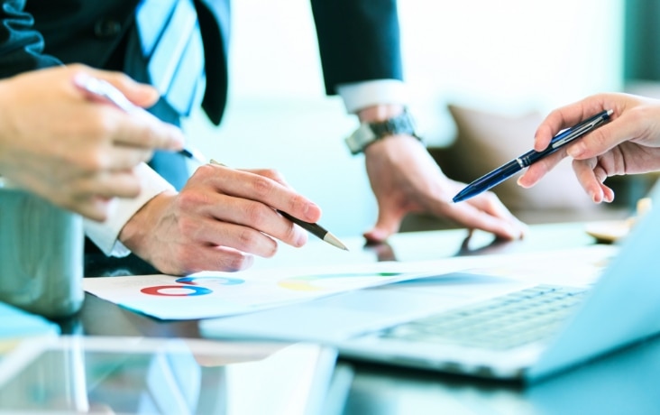 データ分析資料をもとに打ち合わせを行うビジネス担当者