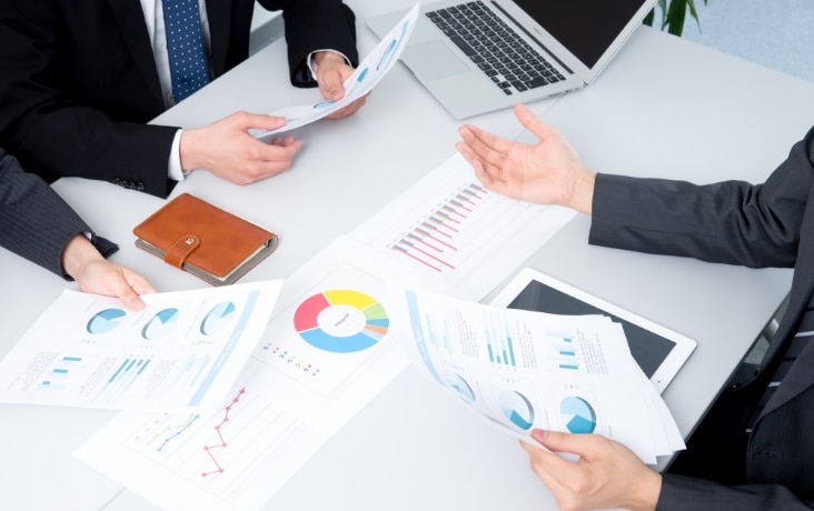 データ分析資料を確認しながら打ち合わせを行うビジネス担当者