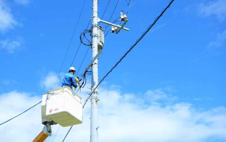 高所作業車で電柱設備を点検する作業員
