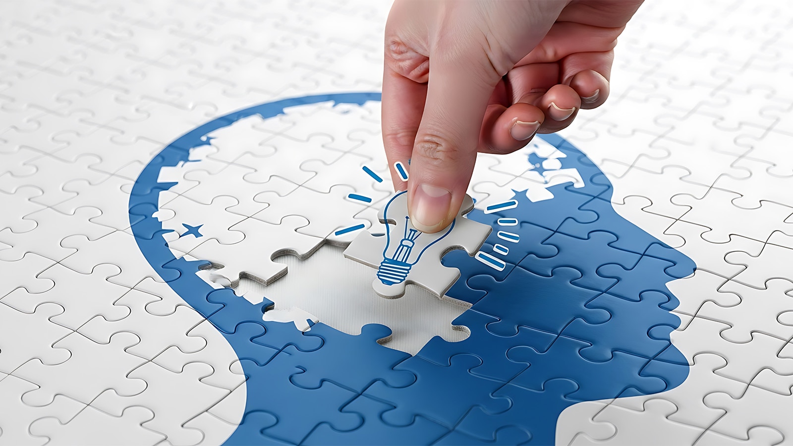 アイデア創出を表す電球ピースを頭部シルエットにはめ込むパズルイメージ