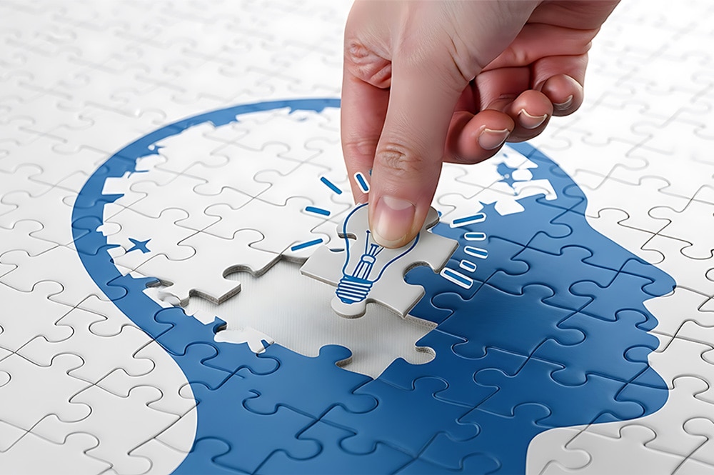 アイデア創出を表す電球ピースを頭部シルエットにはめ込むパズルイメージ