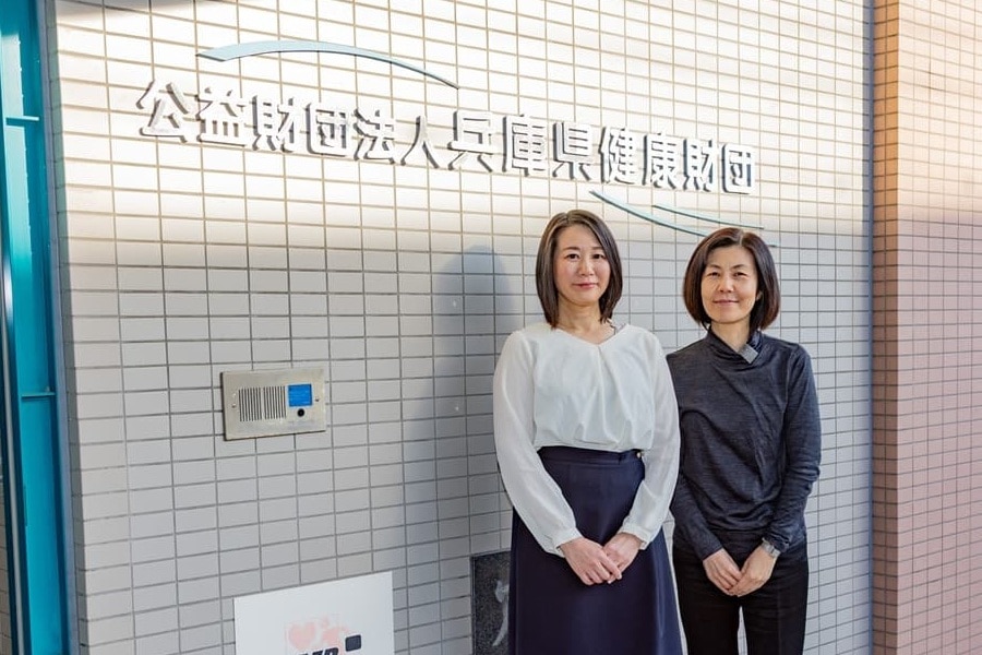 社名の前に立っている女性二人