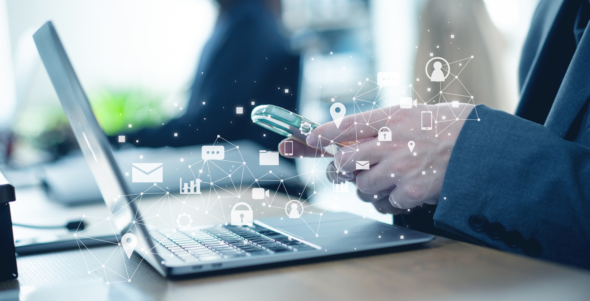 PCの前でスマートフォンを触っている人の画像