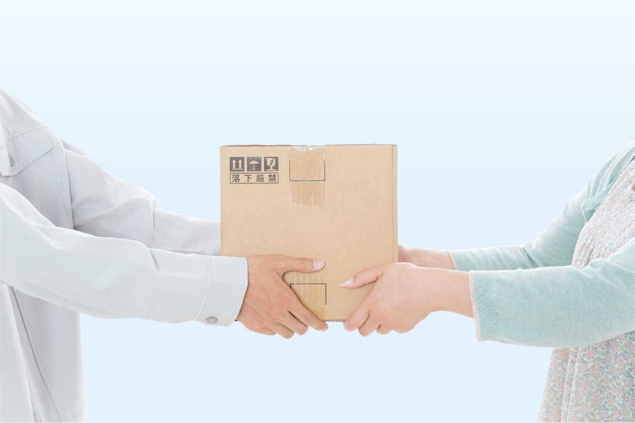 配達員が女性に荷物を渡している手元