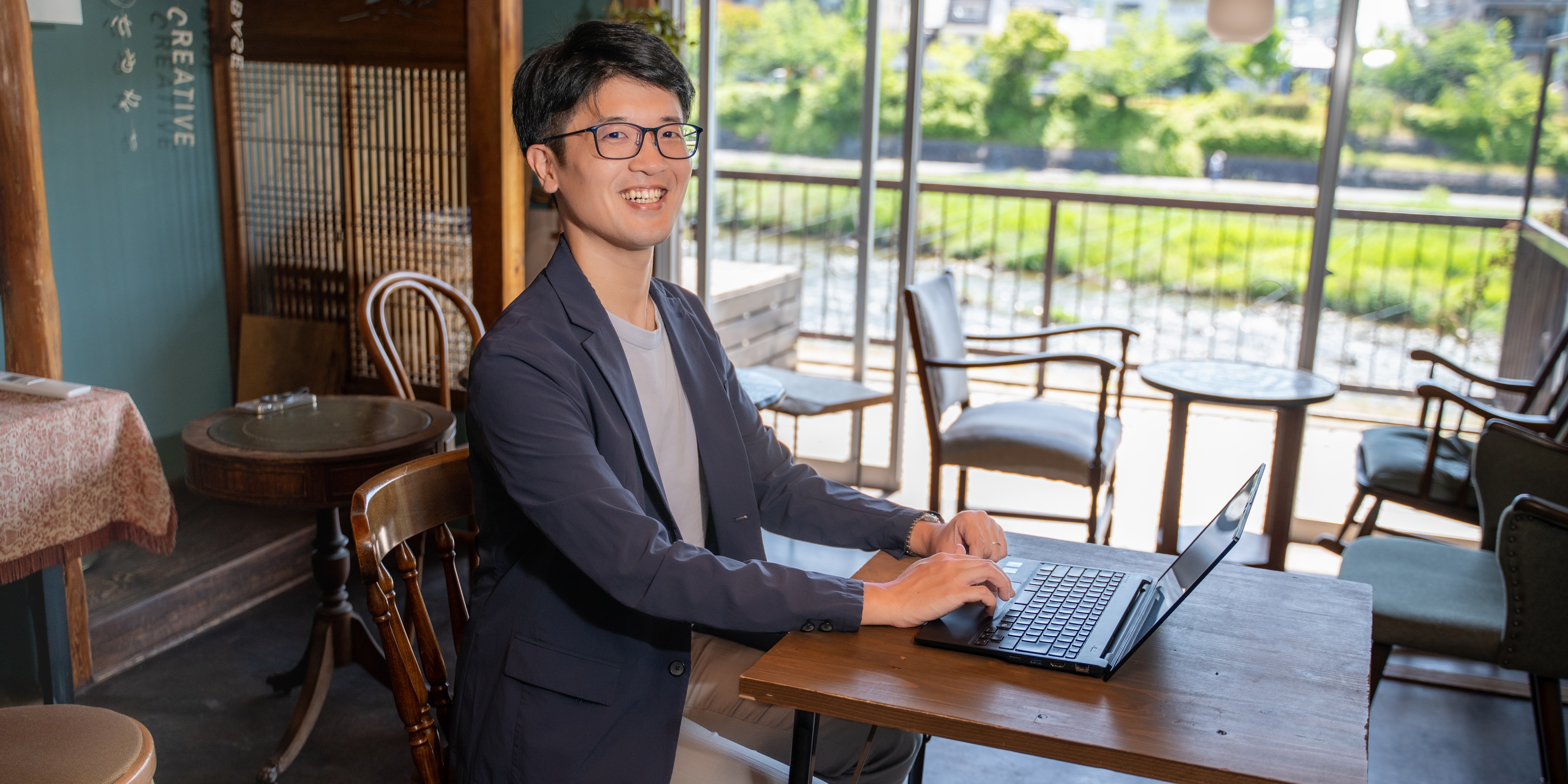 際の席でノートPCを開き、笑顔を見せる畠山謙人税理士事務所の代表税理士 畠山謙人氏