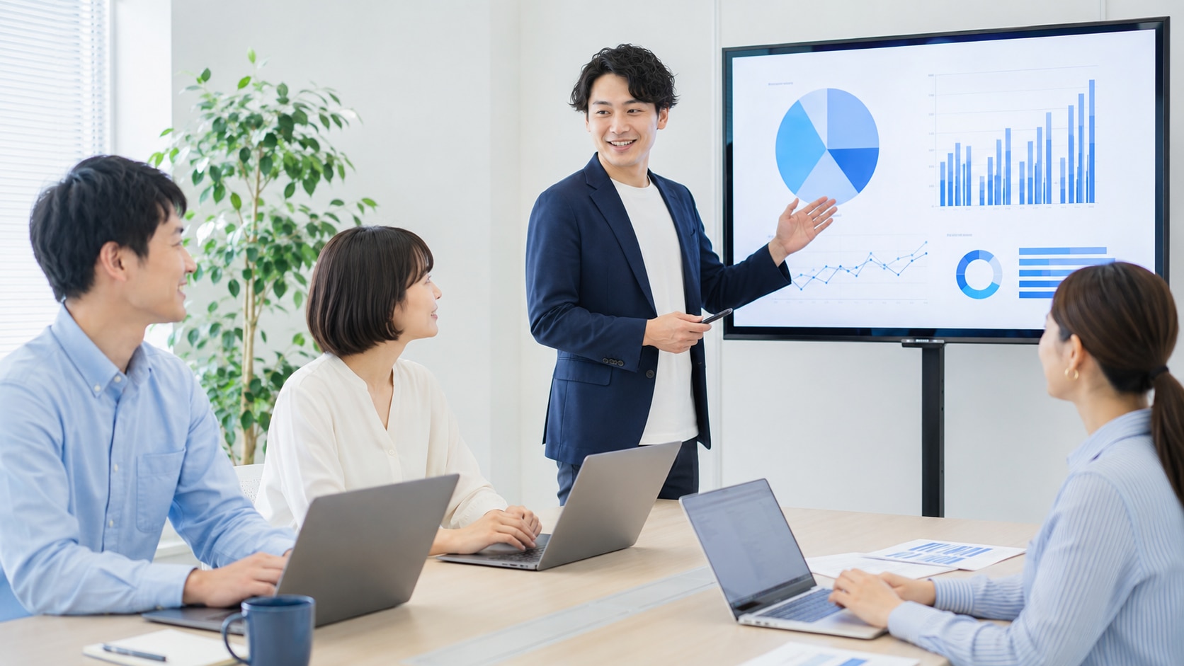 明るくコンパクトな会議室で、少人数の日本人社員チームがノートPCとスクリーンを使ってデジタルスキル研修を受けている様子