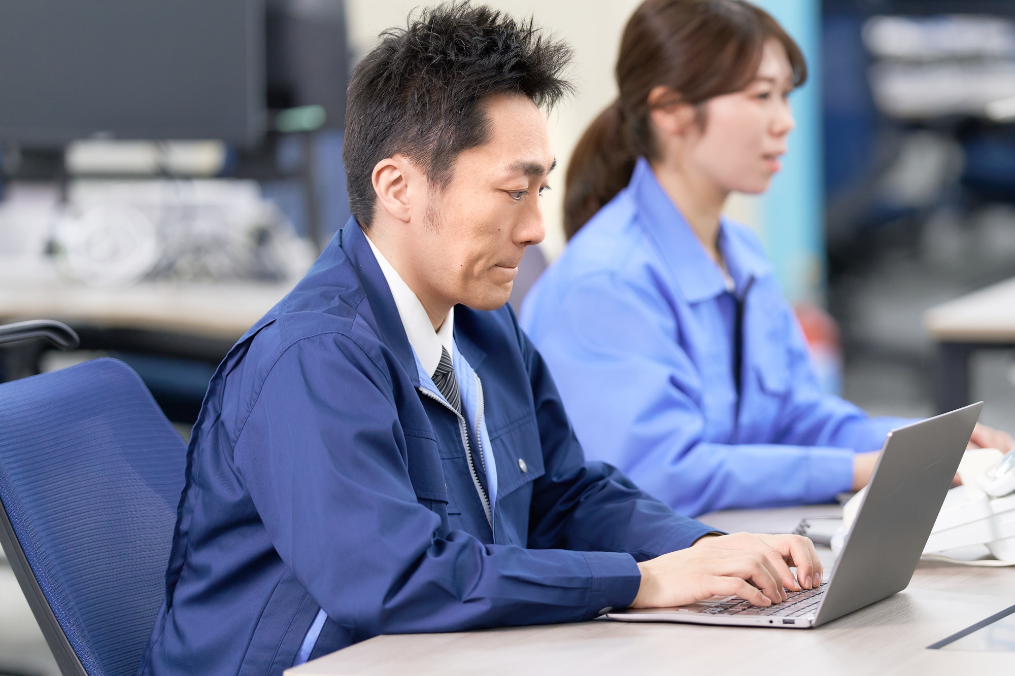 作業着でデータ入力を行う工場スタッフの仕事風景