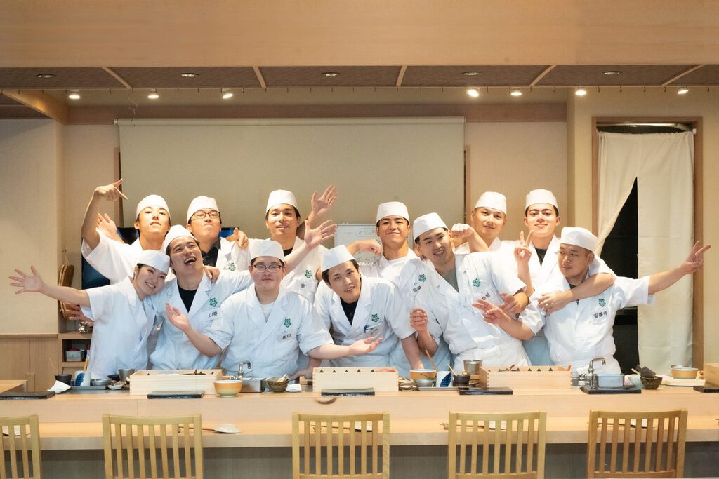寿司職人養成コース40期の受講生と講師がカウンターに並ぶ集合写真